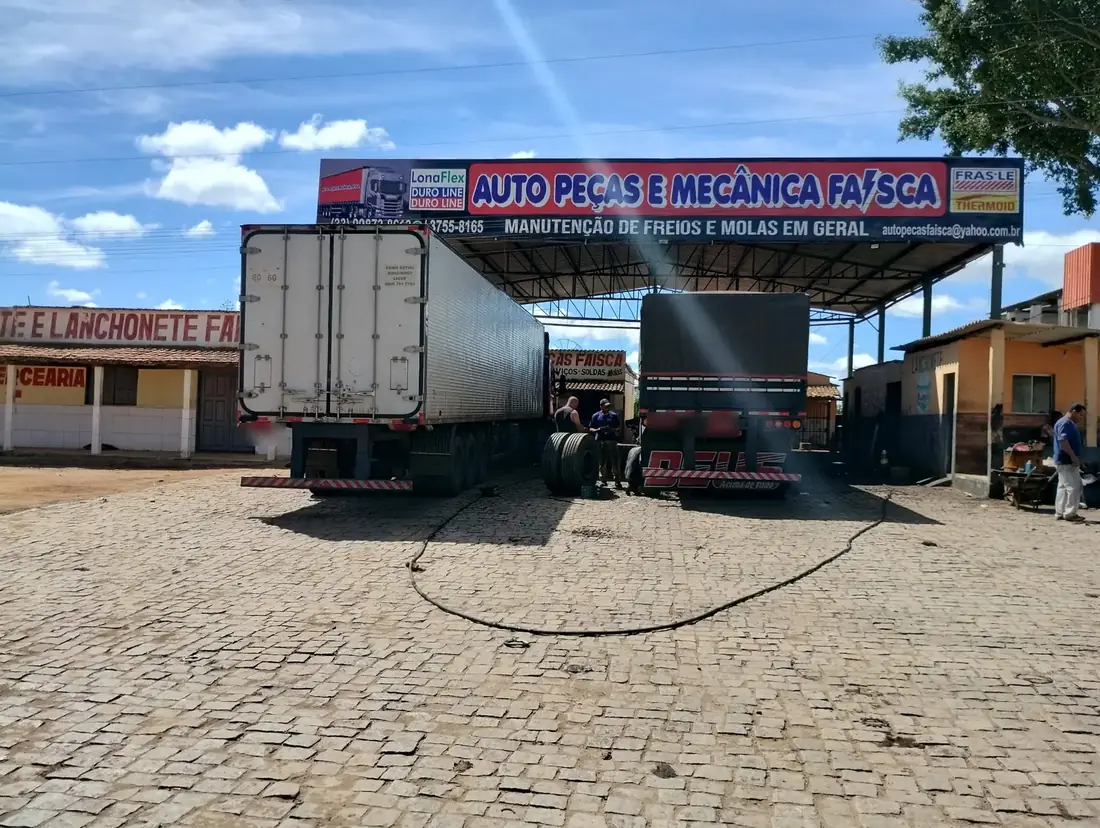 Fachada da Auto Peças e Mecânica Faísca com a placa e duas carretas entrando no pátio