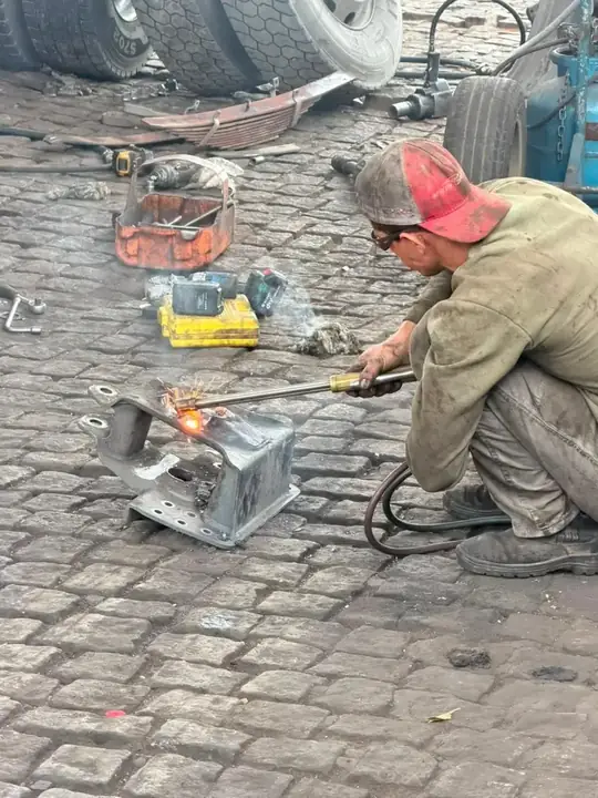 Mecânico cortando suporte de mola com maçarico
