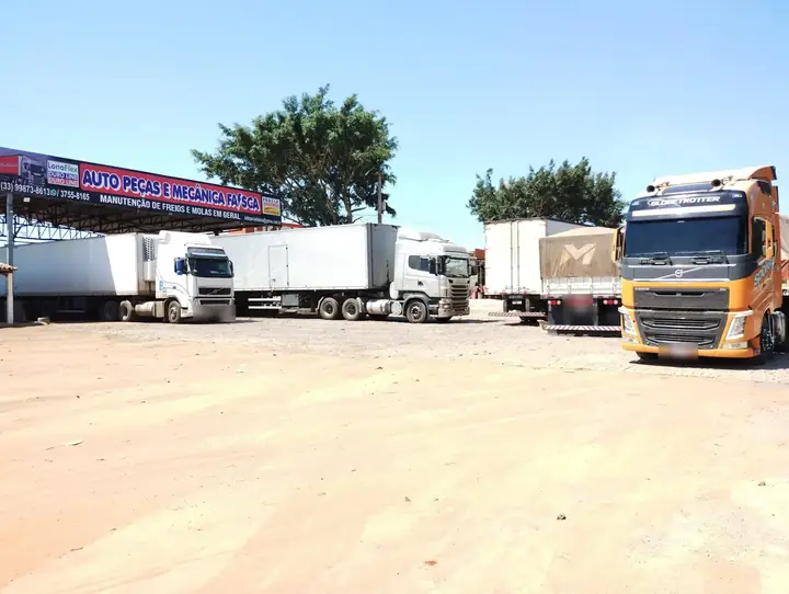 Pátio amplo da Faísca com carretas estacionadas e a placa da oficina